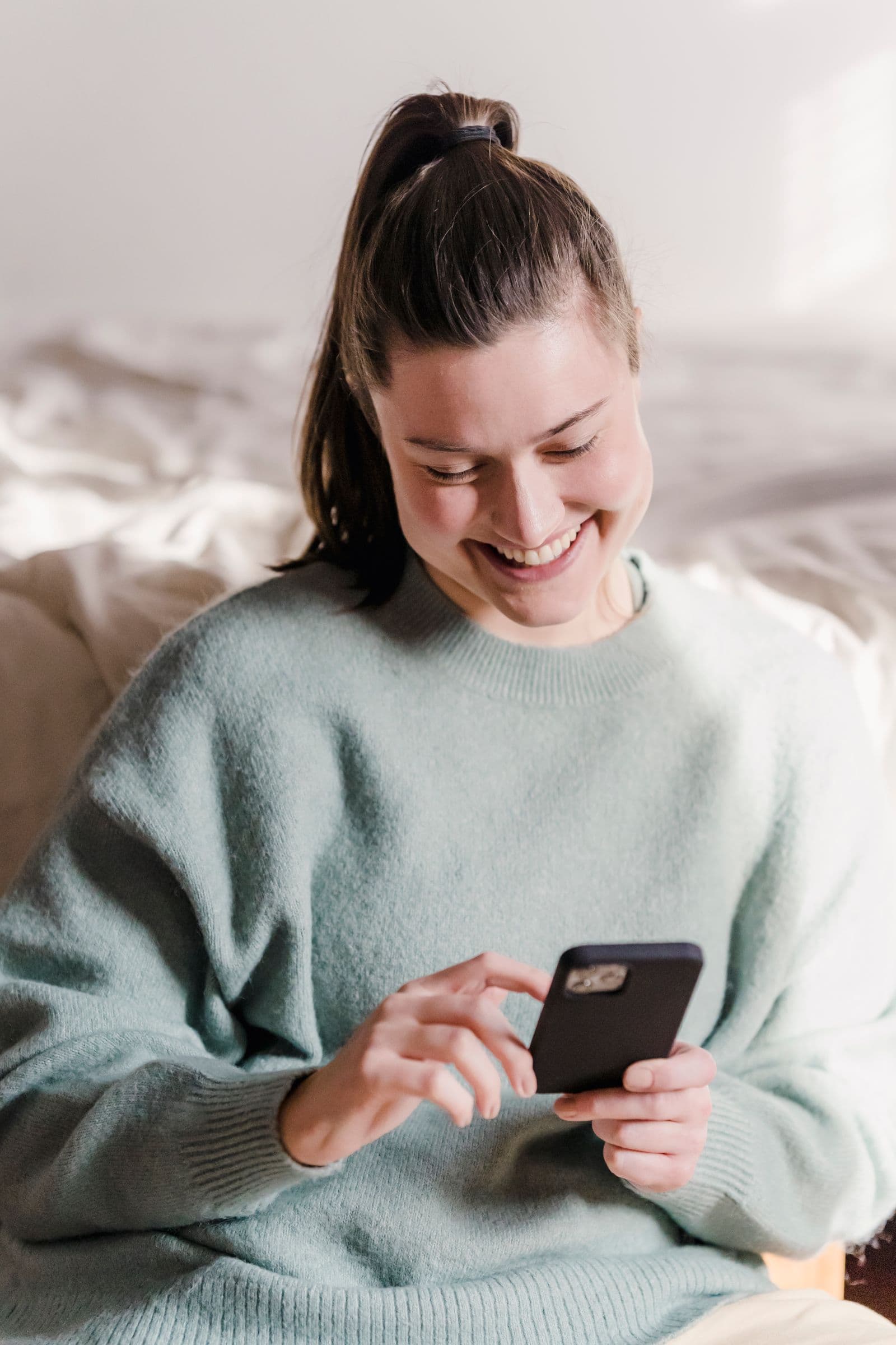 A smiling woman reading a message on her phone