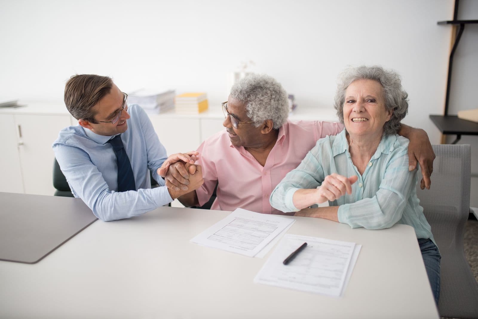 An insurance agent with smiling clients over their policy paperwork