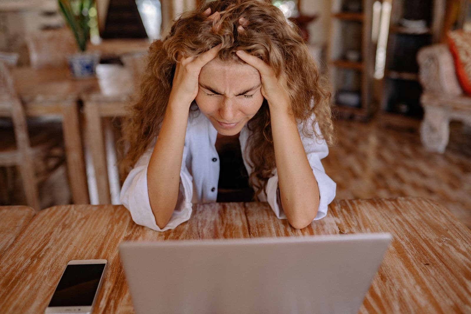 A stressed business owner with her head in her hands at a laptop