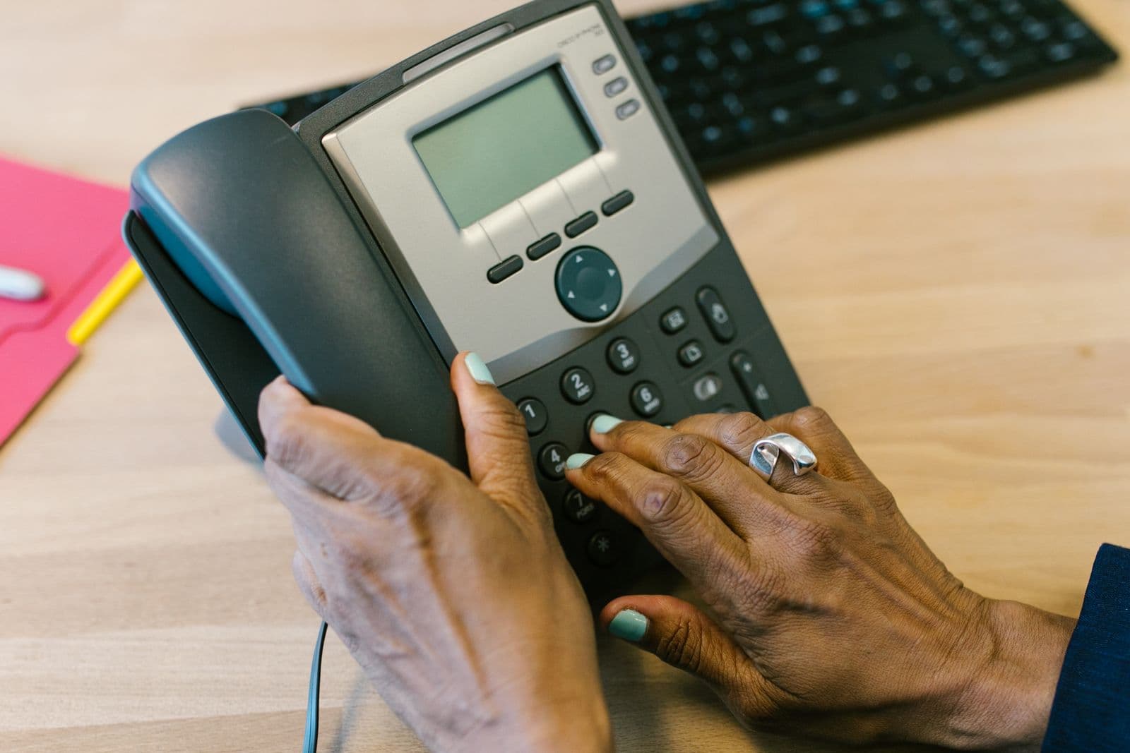 Hands dialling a number on an office desk phone