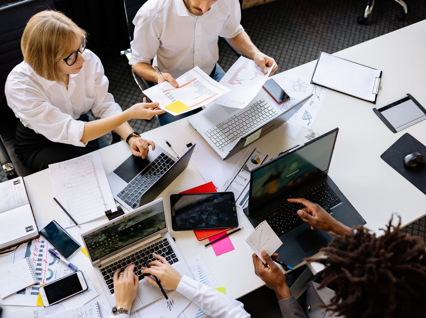 Overhead view of a team reviewing documents and laptops around a table