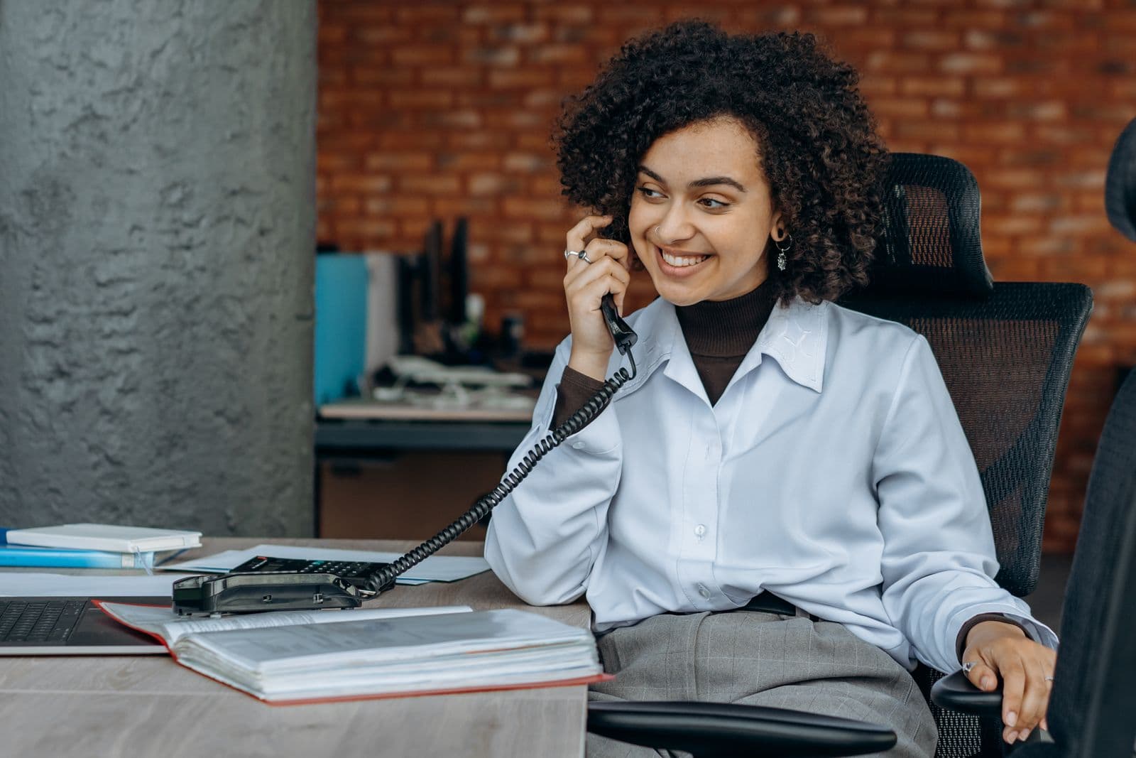 A smiling woman taking a call at her office desk