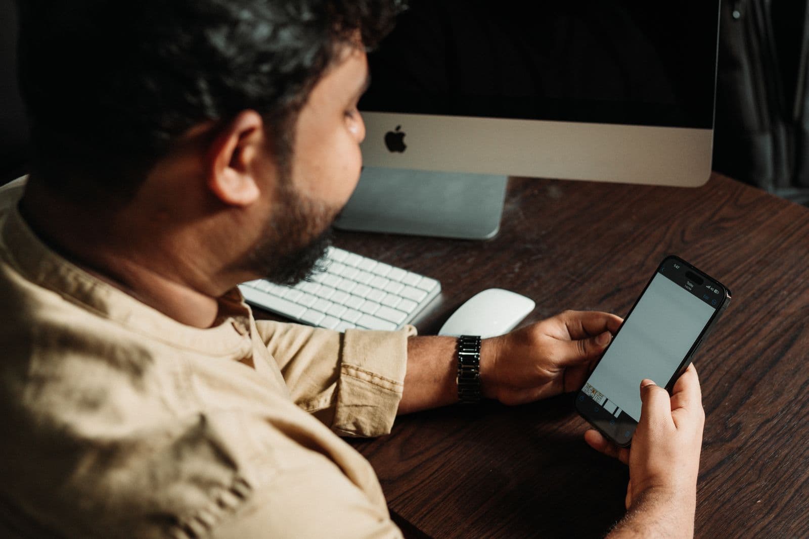 A man at his desk checking his phone for a reply