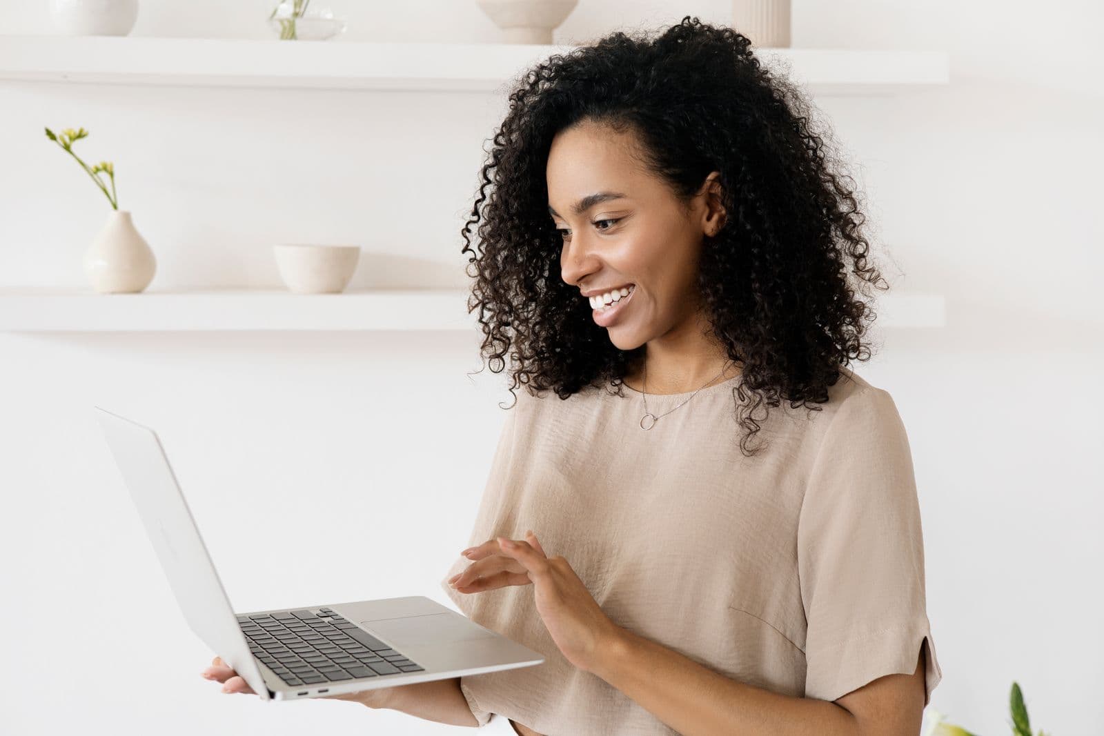 A smiling woman reading a reply on her laptop