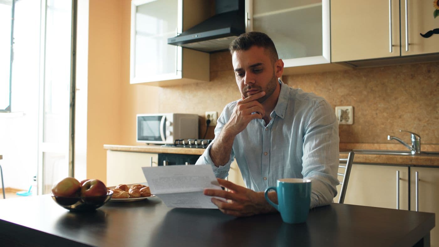 A man reading a letter at his kitchen table