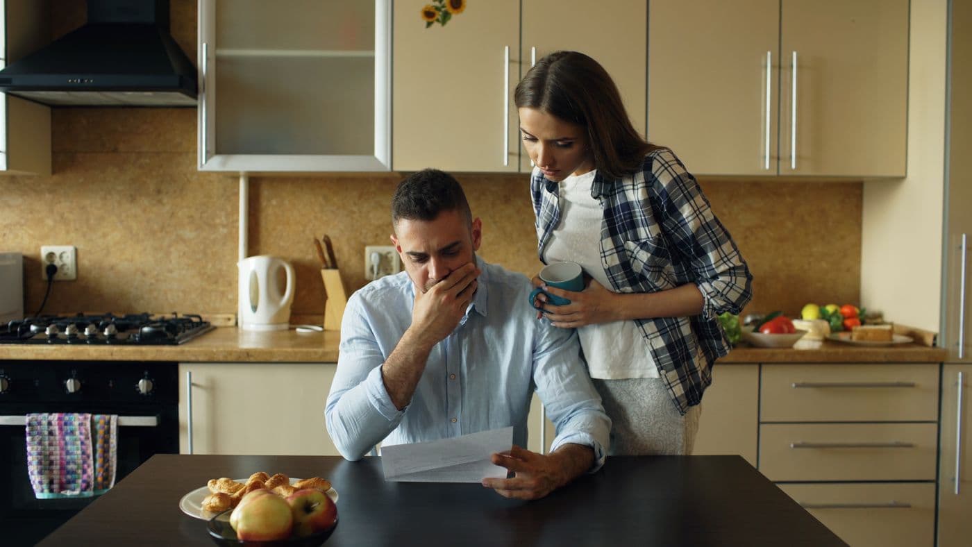 A couple looking concerned over a document in their kitchen