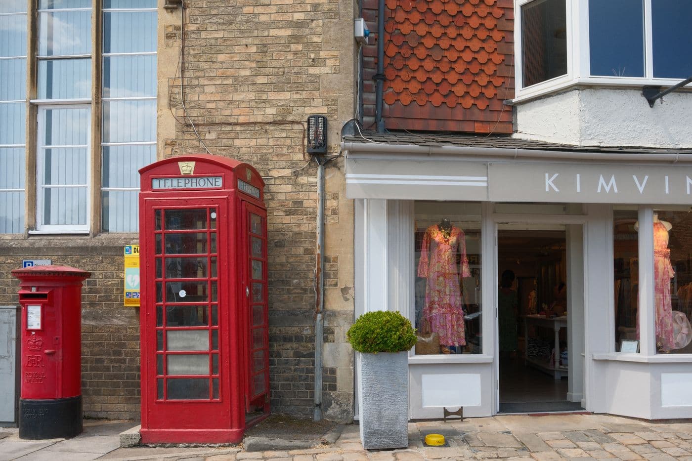 A red telephone box and post box outside a shop