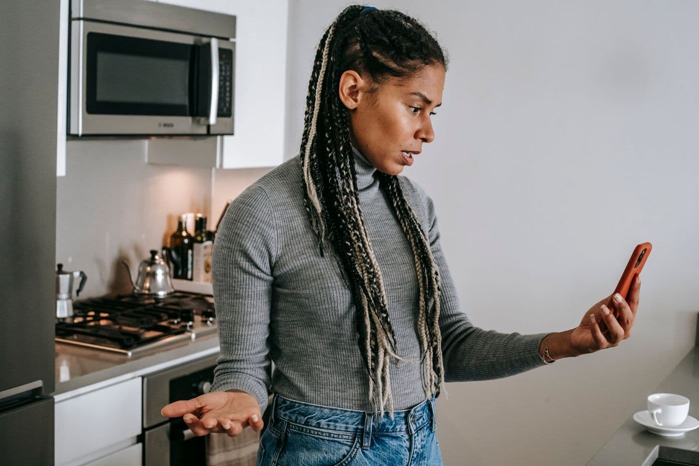 A frustrated woman looking at her phone in her kitchen