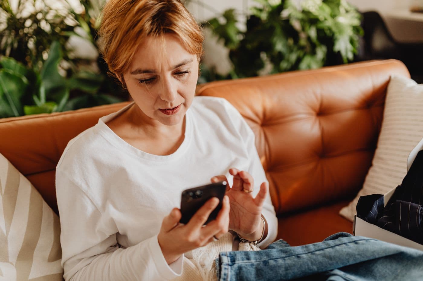 A woman using her smartphone on the sofa