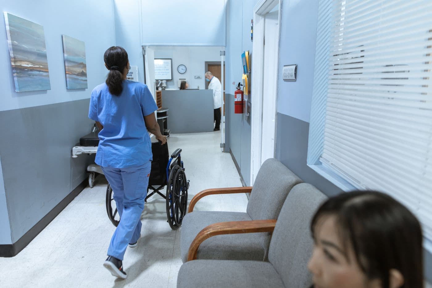 A nurse pushing a wheelchair through a hospital corridor