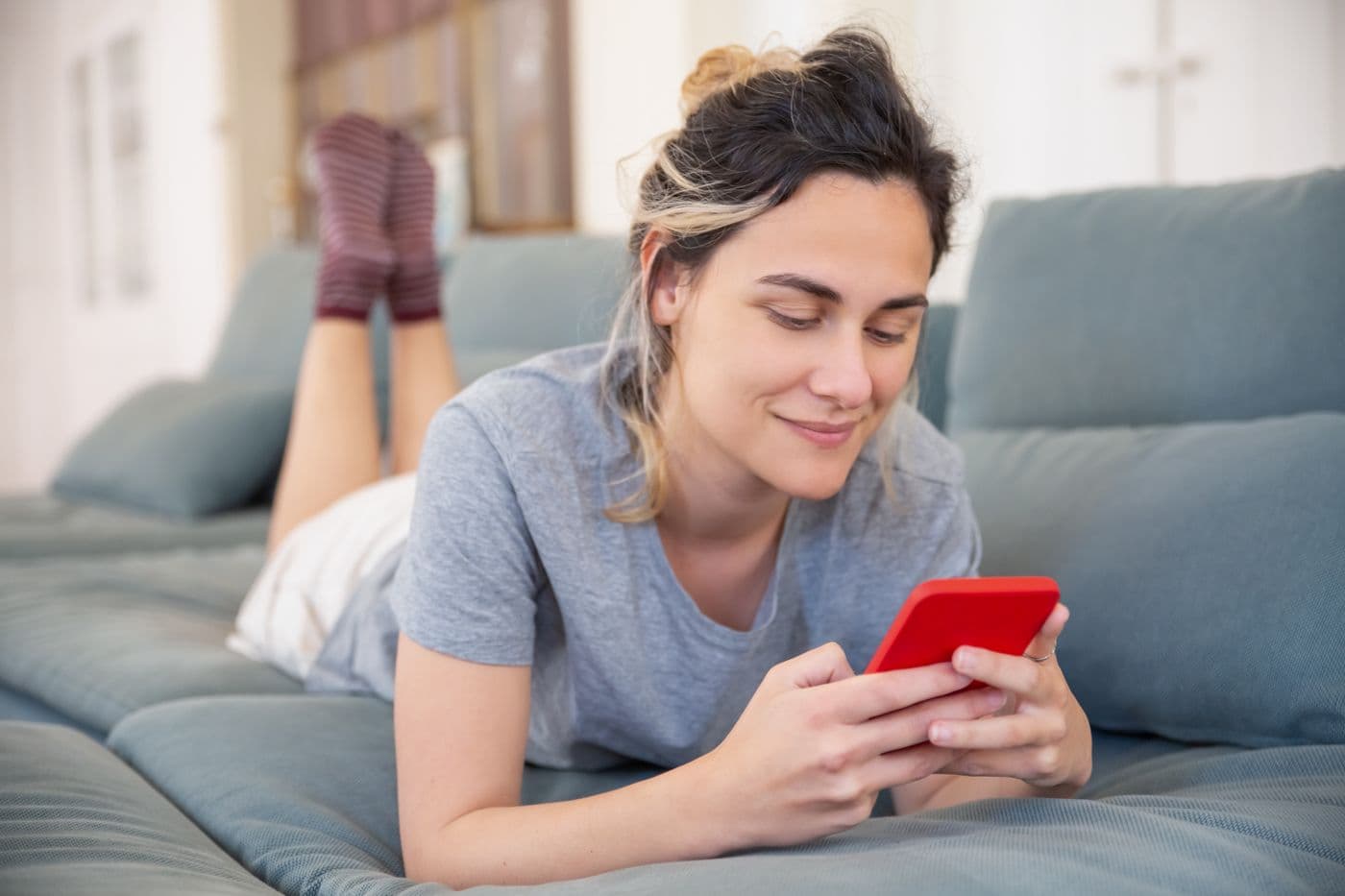 A young woman using her smartphone on the sofa