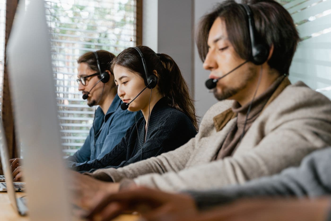 Three contact centre agents with headsets at work