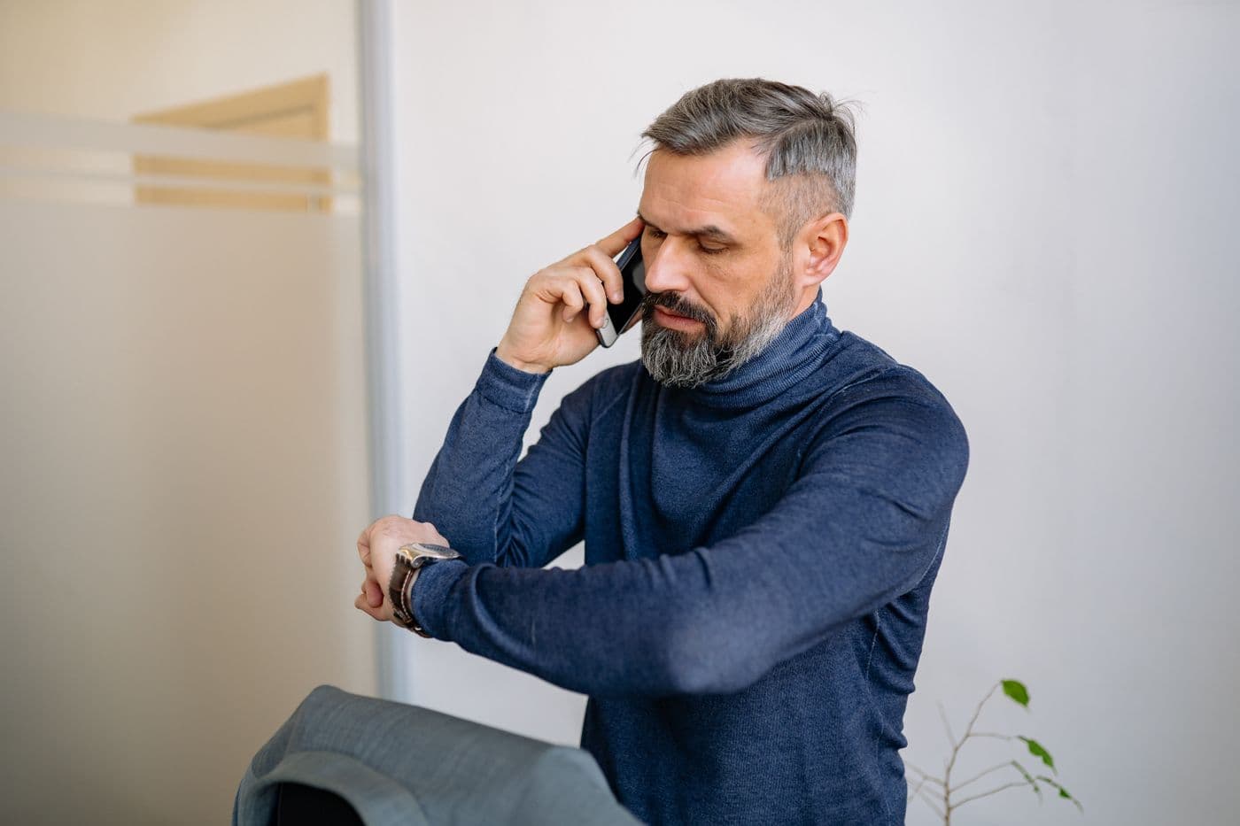 A man on the phone checking the time while he waits